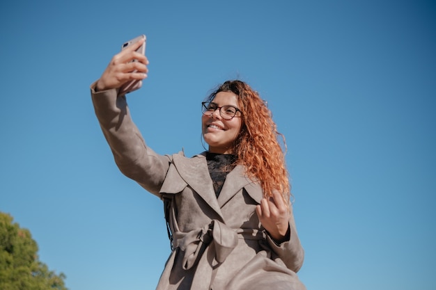 Linda menina morena latina fazendo um autorretrato com o celular ao ar livre