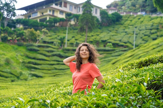 Linda menina morena posando no meio do vale do chá, entre arbustos de chá verde.