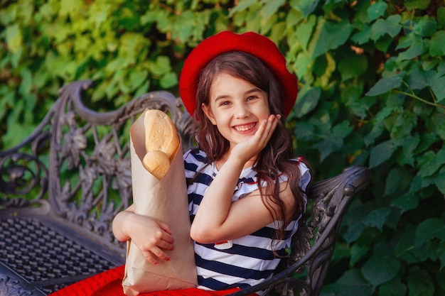 Linda menina morena segurando uma baguete francesa