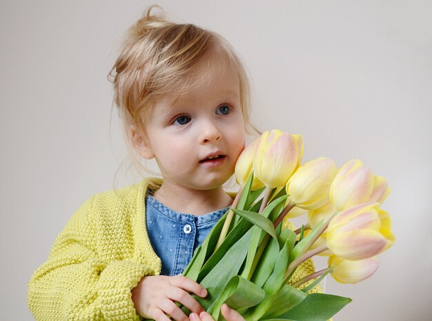 Linda menina, segurando um buquê de tulipas amarelas