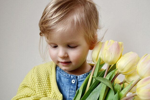 Linda menina, segurando um buquê de tulipas amarelas