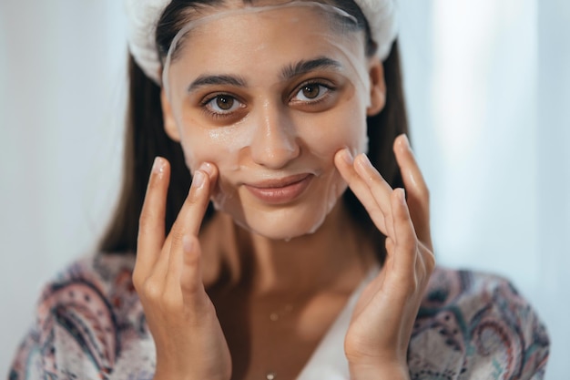 Linda modelo aplicando creme cosmético no rosto