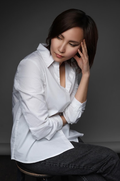 Linda modelo asiática vestindo uma camisa branca enorme e posando no estúdio fotográfico