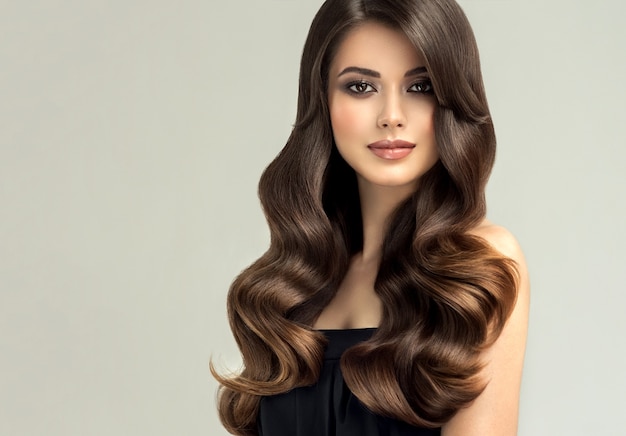 Linda modelo com cabelo comprido e bem penteado. Excelentes ondas de cabelo. Arte para cabeleireiro e cuidados com os cabelos