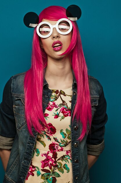 Linda modelo com cabelo rosa e maquiagem usando grandes óculos escuros
