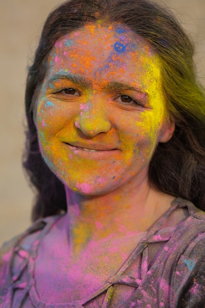 Linda modelo morena com cabelos ondulados coberto com tinta seca colorida Holi no deserto