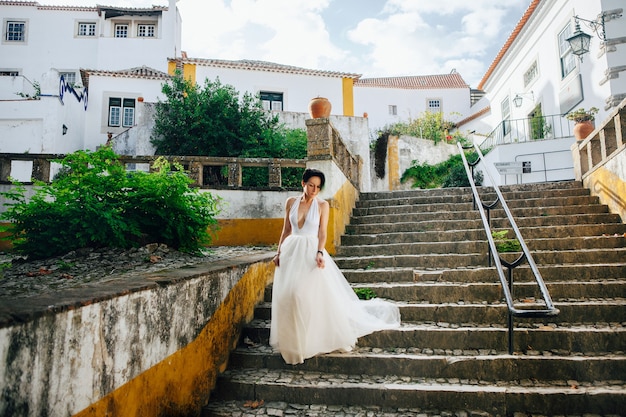 Linda modelo usando um vestido branco posando ao lado de um antigo castelo