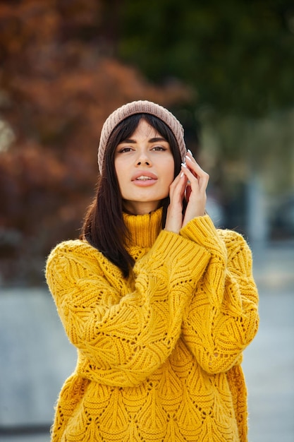 Linda morena europeia vestida com um suéter de lã amarelo e chapéu do lado de fora