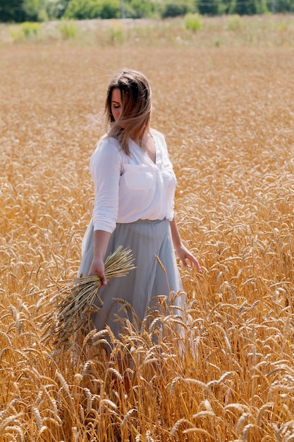 Linda morena mais senhora de tamanho no campo de trigo ao pôr do sol.