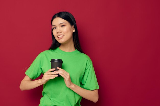 Linda morena posando em uma camiseta verde óculos pretos descartáveis fundo vermelho inalterado