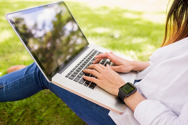 Linda morena usando o laptop no parque