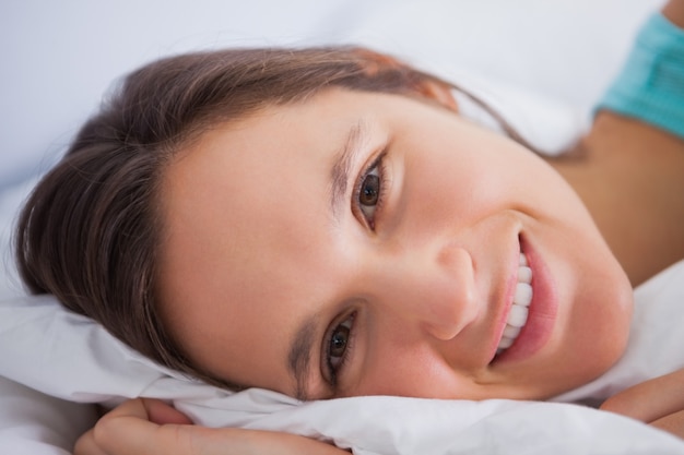 Linda mujer acostada en la cama mirando a la cámara