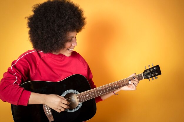 Linda mujer afroamericana en estudio tocando la guitarra