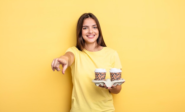 Linda mujer apuntando a la cámara escogiéndote. concepto de café para llevar