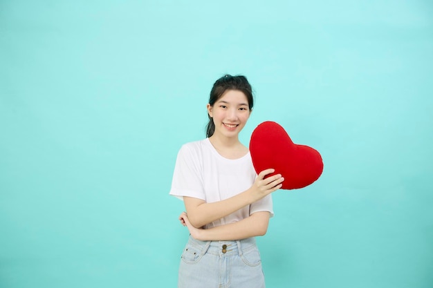 Linda mujer asiática alegre cabello negro sonríe con forma de almohada de corazón