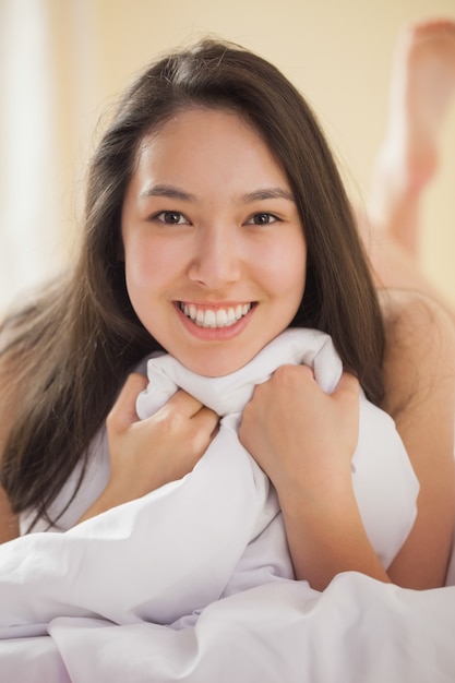 Linda mujer asiática joven sosteniendo su duvet sonriendo