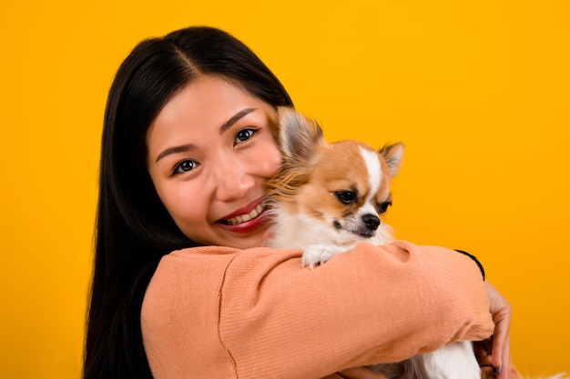 Linda mujer asiática con su amante del perro chihuahua chihuahua La felicidad de una chica que ama a su perro El amor de la gente y la sesión de fotos de perros lindos en el estudio naranja