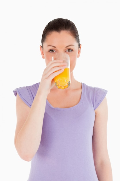 Linda mujer bebiendo un vaso de jugo de naranja mientras está de pie