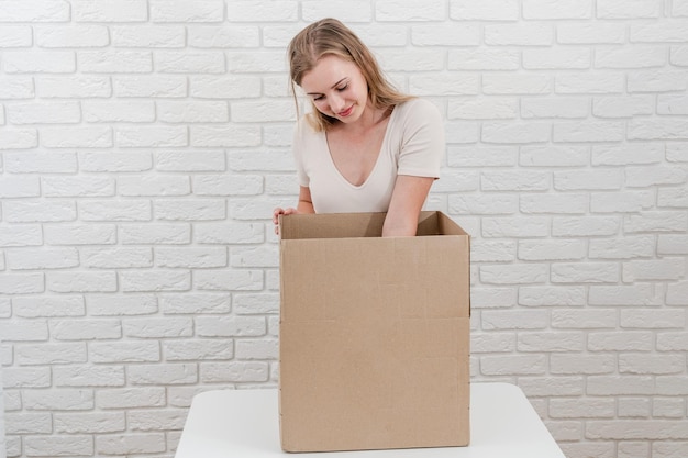 Linda mujer con caja de cartón abierta entregando un paquete