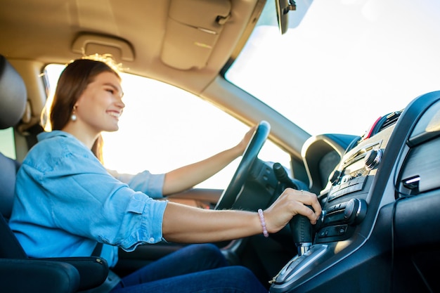 Linda mujer cantando mientras conduce un automóvil en un viaje por carretera el día de verano