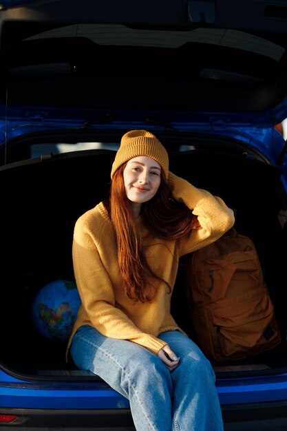 Linda mujer casual de pelo rojo viaja al aire libre en coche