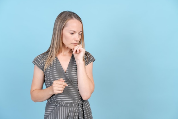 Linda mujer caucásica aislada sobre fondo azul con vestido sintiéndose triste