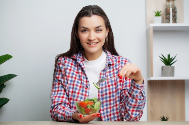 Foto linda mujer come ensalada de verduras con muchas vitaminas