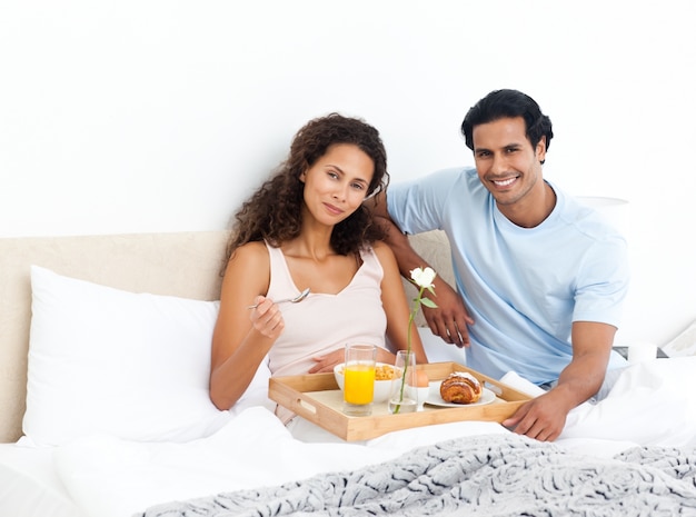 Linda mujer comiendo cereales para el desayuno acostado en su cama