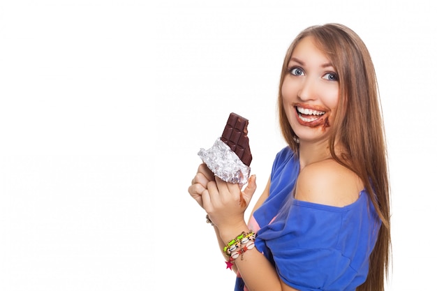 Linda mujer comiendo chocolate con las dos manos, con un poco en la boca. Isolatet en blanco.