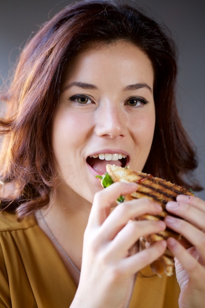 Linda mujer comiendo un club sándwich en un restaurante de pub