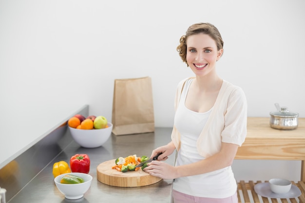 Linda mujer cortando verduras en su cocina