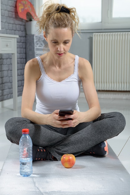 Linda mujer deportiva usando su teléfono inteligente