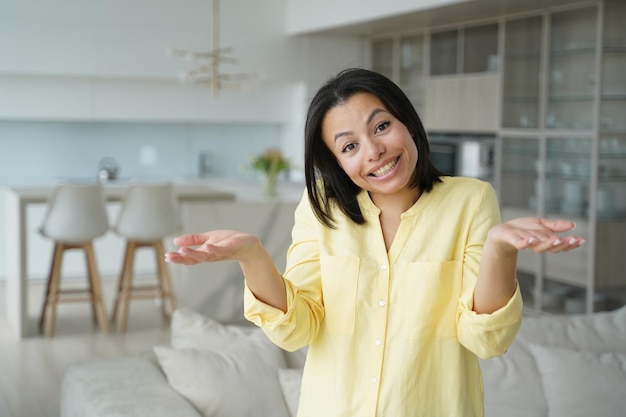 Linda mujer desconcertada feliz no sabe el concepto Chica confundida en la sala de estar en casa