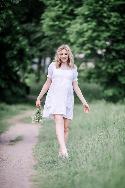 Linda mujer embarazada en un paseo en un día de verano. el concepto de felicidad