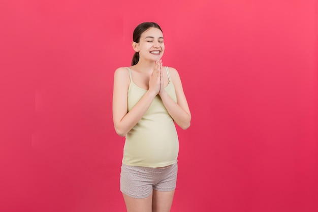 Linda mujer embarazada rezando sobre fondo de color aislado