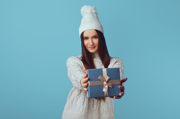 Foto linda mujer emocionada en suéter blanco y sombrero con regalo sorpresa presente