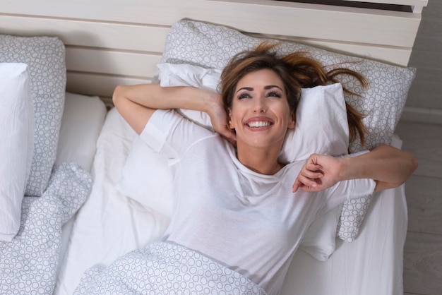 Linda mujer estirándose en la cama después de despertarse