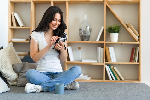 Linda mujer feliz sosteniendo teléfono celular, usando la aplicación de citas móvil para chatear o enviar un mensaje romántico