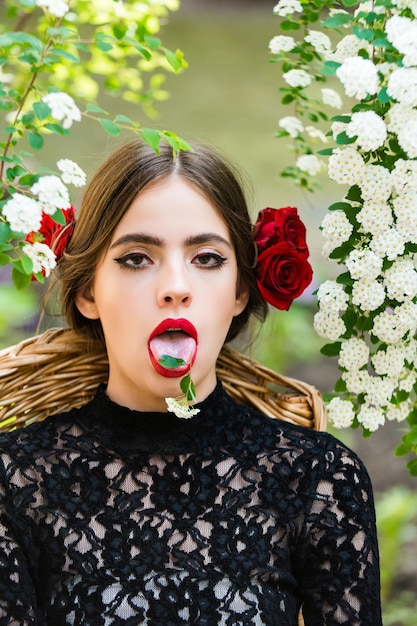 Linda mujer con flor blanca en la lengua en la boca abierta