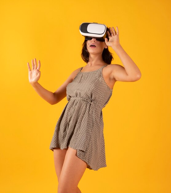 Linda mujer con gafas de realidad virtual en espacio amarillo