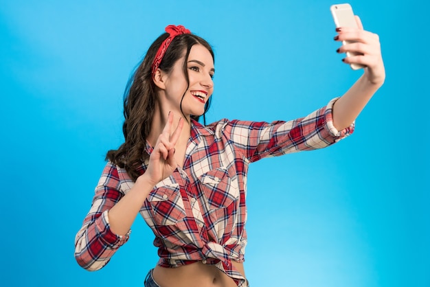 La linda mujer hace un selfie sobre fondo azul.