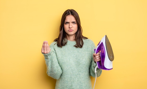 Linda mujer haciendo capice o gesto de dinero, diciéndote que pagues. concepto de ropa de hierro