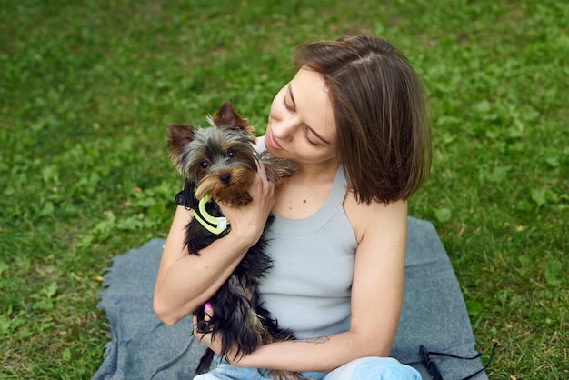 Linda mujer hermosa con el pequeño Yorkshire Terrier en un parque al aire libre Retrato de estilo de vida