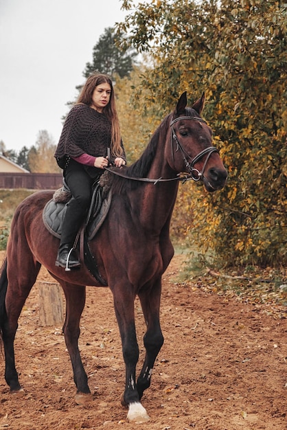 Linda mujer joven a caballo en el bosque de otoño