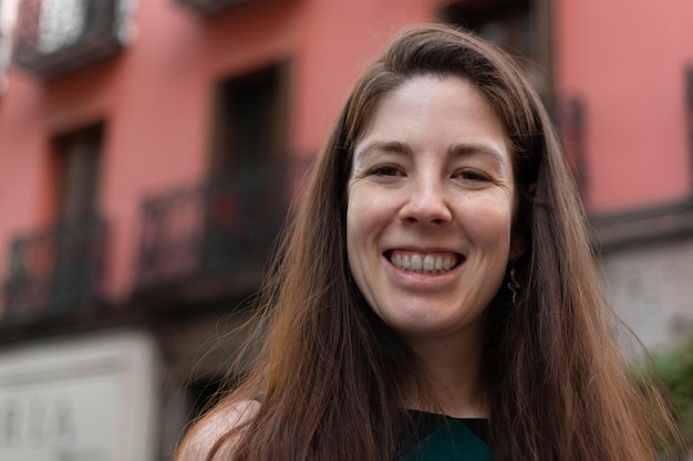 Linda mujer joven con un encantador sentido del humor apoyada contra una pared exterior roja