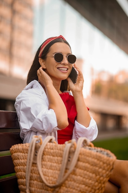 Una linda mujer joven en gafas de sol con un teléfono en las manos