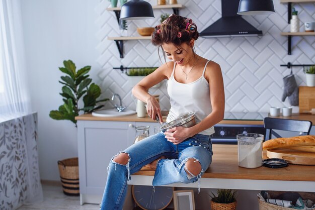 Linda mujer joven haciendo masa en la cocina