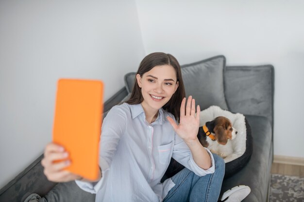 Una linda mujer joven haciendo selfie con su cachorro y mirando feliz