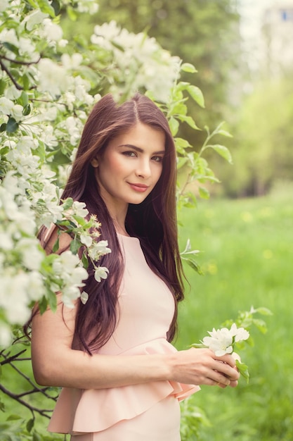 Linda mujer joven con retrato de moda al aire libre de flores