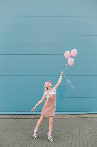 Linda mujer joven en ropa rosa de pie con globos